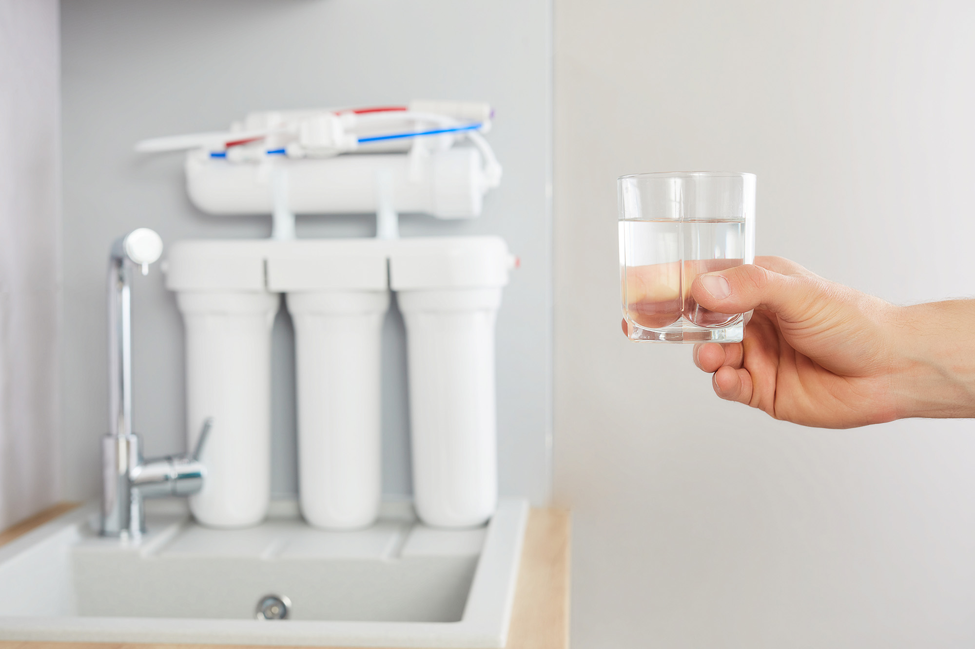 Men s hand holds glass clear water tap reverse osmosis filter background